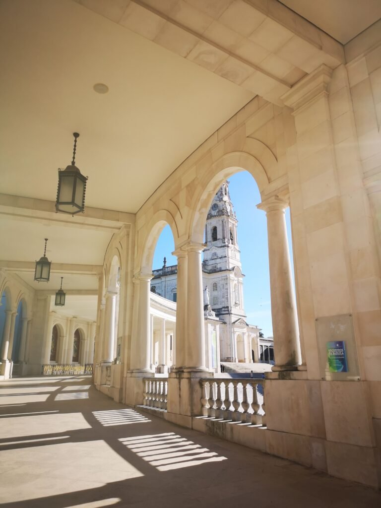 The bell tower of the Basilica of Our Lady of the Rosary, framed by the arches of the colonnade at the Sanctuary of F&aacute;tima