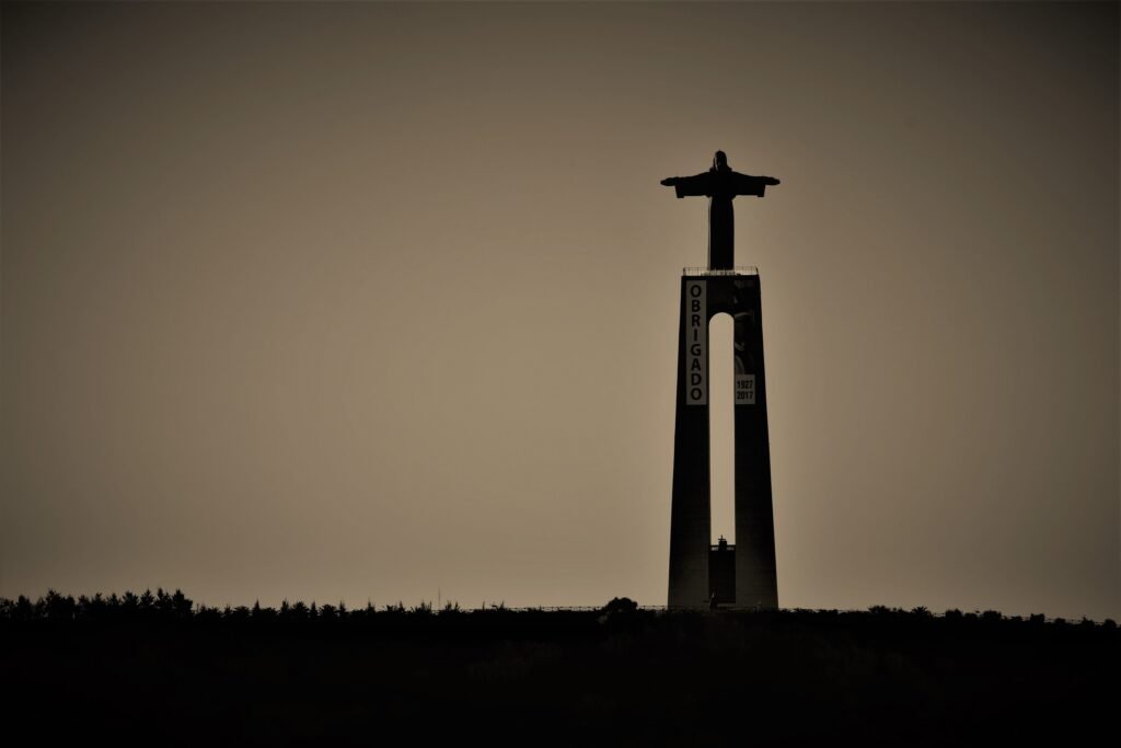 The Christ the King statue in silhouette against an evening sky, above Almada across the river from Lisbon