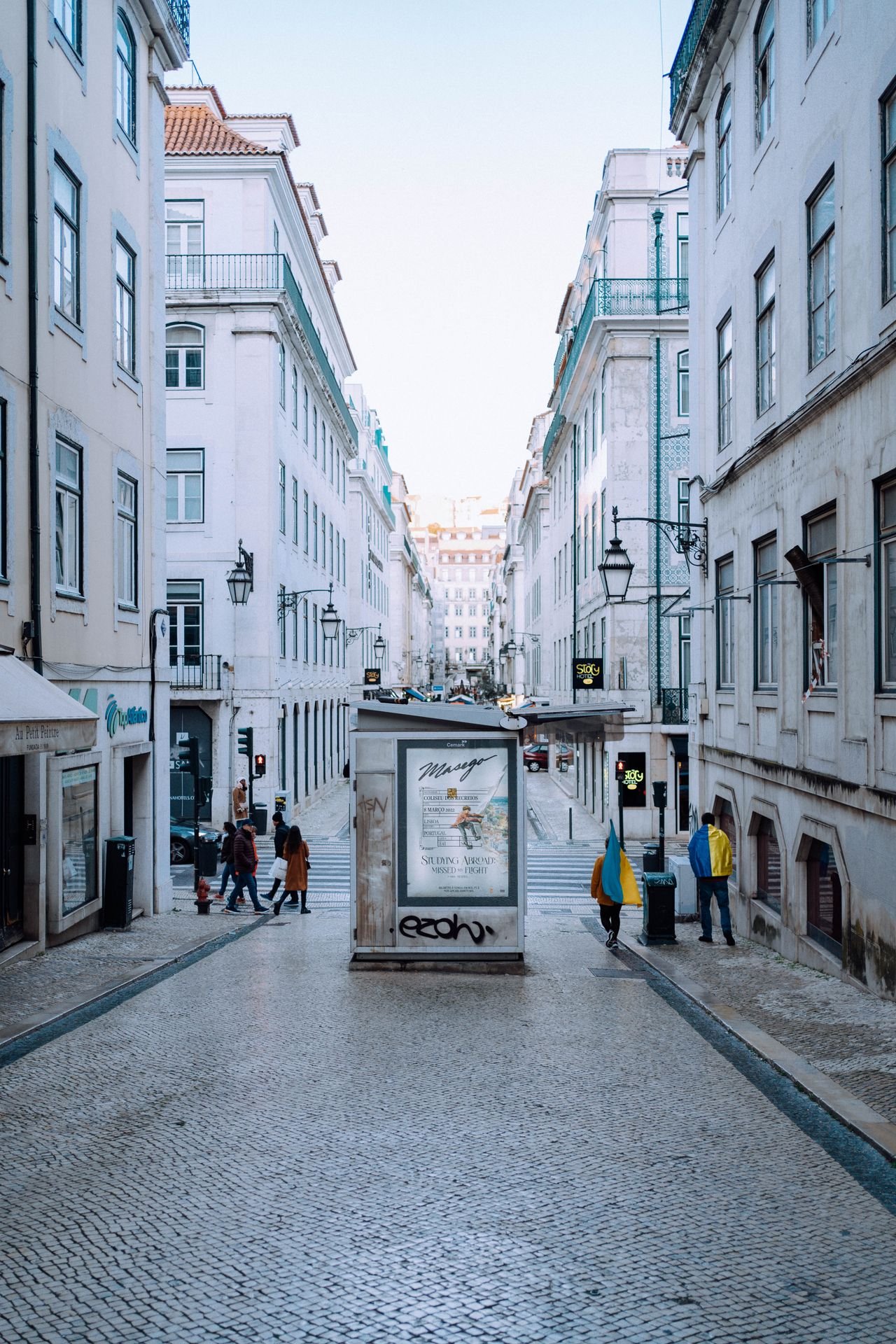 Pedestrians walking on Rua Augusta in Lisbon's historic district with classic European architecture.